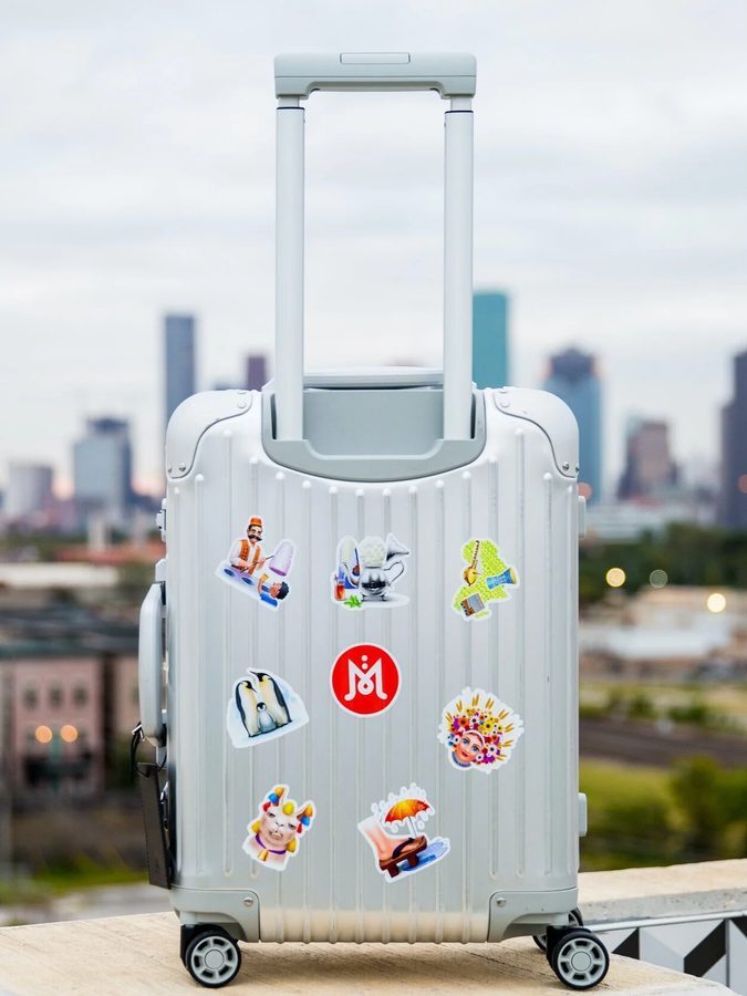 A suitcase covered in Mojimix stickers, city skyline behind it